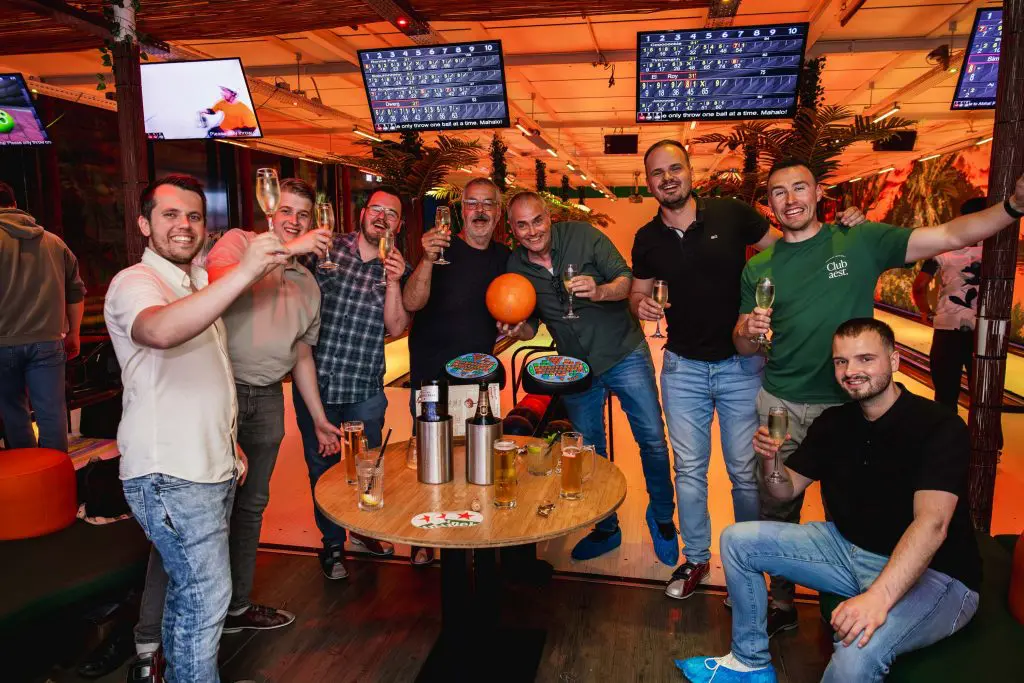 Groep mannen poseren bij de bowlingbaan van Aloha