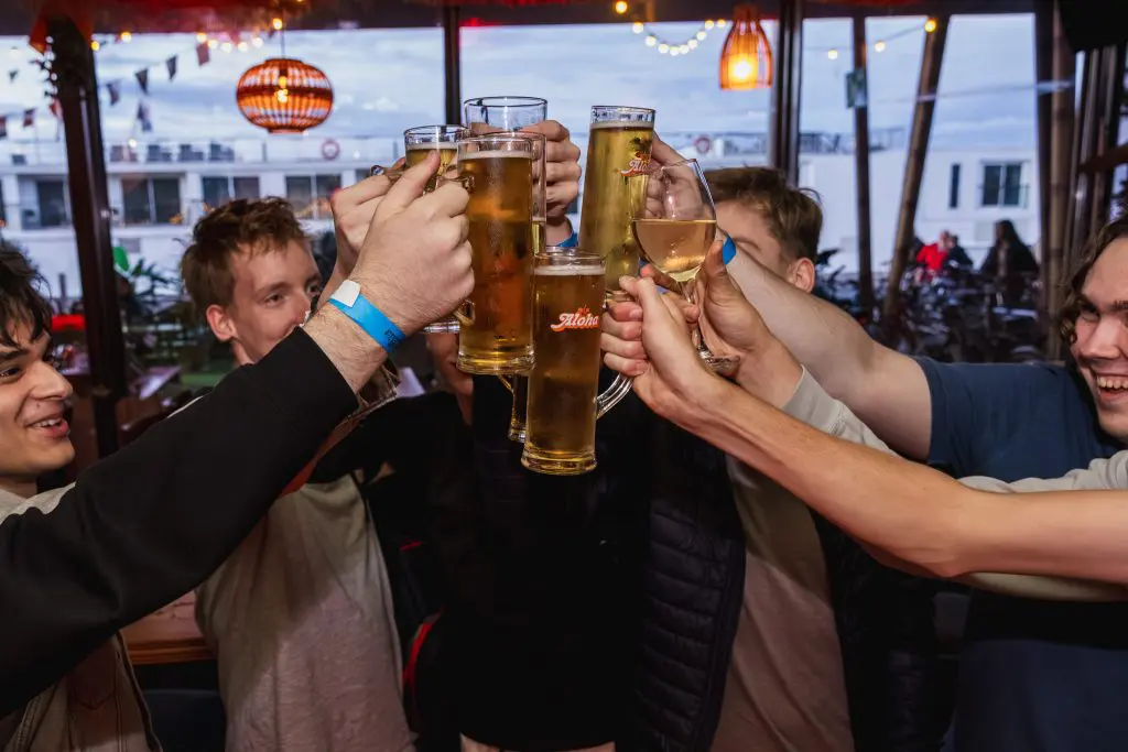 Mensen die proosten met bier en wijn bij Aloha Amsterdam