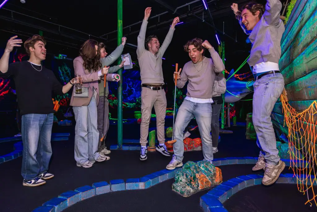 Groep jongens en meiden juichend op mingolf baan