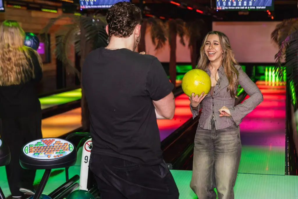 Collega’s tijdens een bedrijfsuitje in Amsterdam bij een kleurrijke bowlingbaan, terwijl één van hen lacht met een bowlingbal in haar hand.
