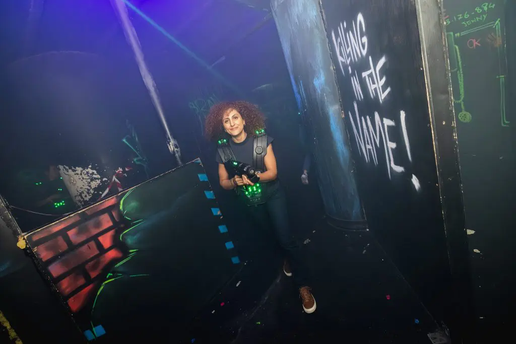 Vrouw speelt laser tag in een donkere, neonverlichte arena