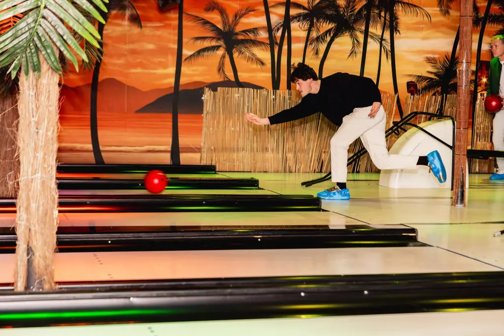 Man gooit een bowlingbal tijdens een bedrijfsuitje in tropisch aangeklede bowlingbaan in Amsterdam.