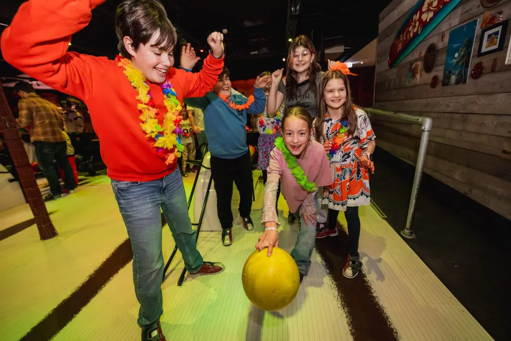 Meisje gooit bowlingbaan terwijl andere kinderen haar toejuichen