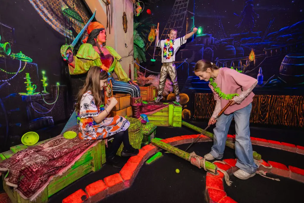 Drie meisjes spelen minigolf.