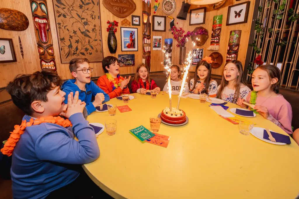 Groep kinderen aan een ronde tafel met een taart in het midden
