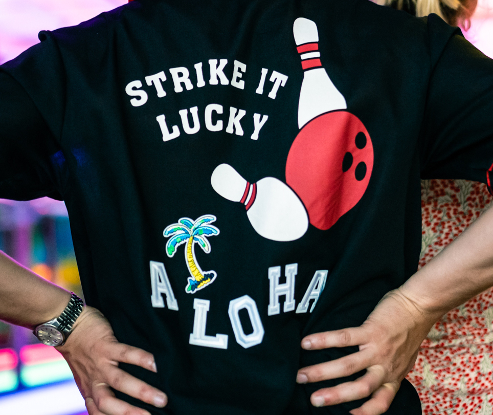 Het Aloha bowling-shirt. Met de tekst: strike it lucky, Aloha.